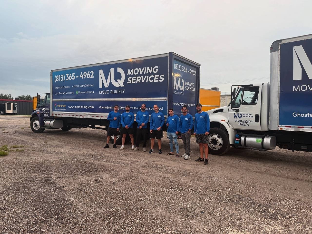 The full Move Quickly LLC moving team in blue uniforms standing in front of three branded moving trucks in Tampa, Florida
